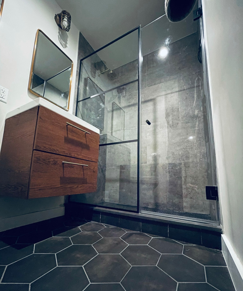 Kleines Industrial Badezimmer En Suite mit braunen Schränken, freistehender Badewanne, Porzellan-Bodenfliesen, grauem Boden, Falttür-Duschabtrennung, Einzelwaschbecken und schwebendem Waschtisch in New York