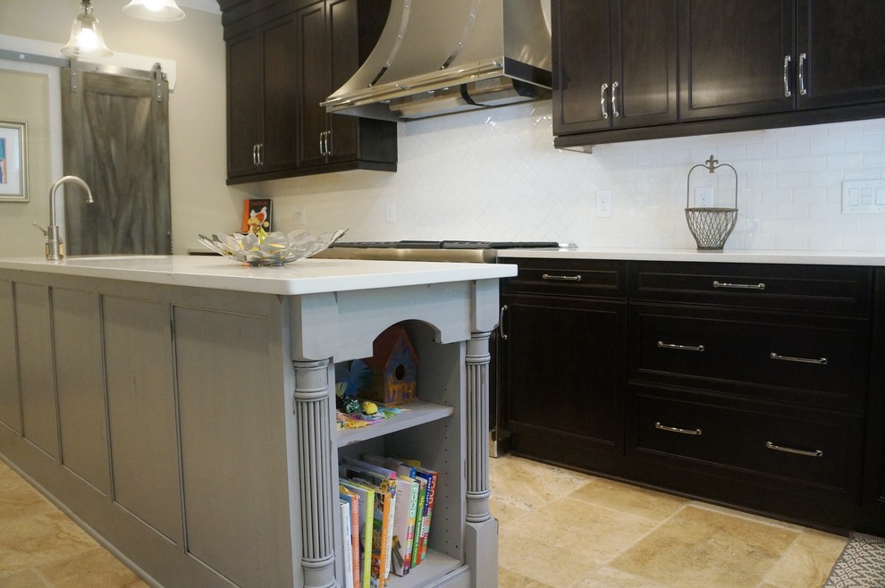 Inspiration for a mid-sized transitional l-shaped travertine floor eat-in kitchen remodel in Raleigh with a farmhouse sink, flat-panel cabinets, dark wood cabinets, quartz countertops, white backsplash, ceramic backsplash, stainless steel appliances and an island