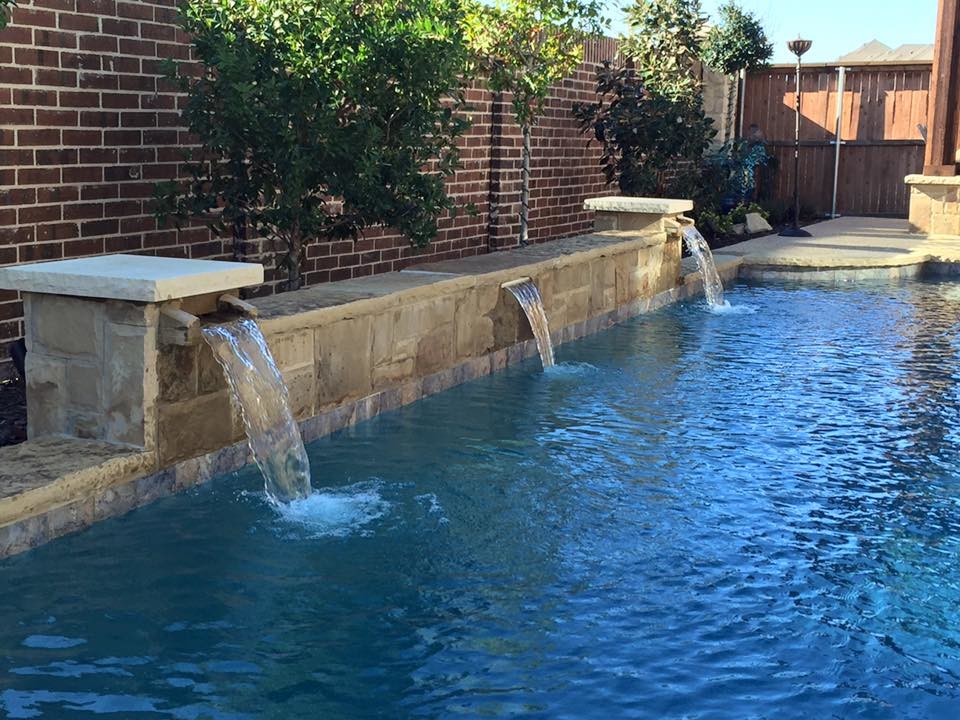 Photo of a small contemporary backyard custom-shaped lap pool in Dallas with a water feature and stamped concrete.