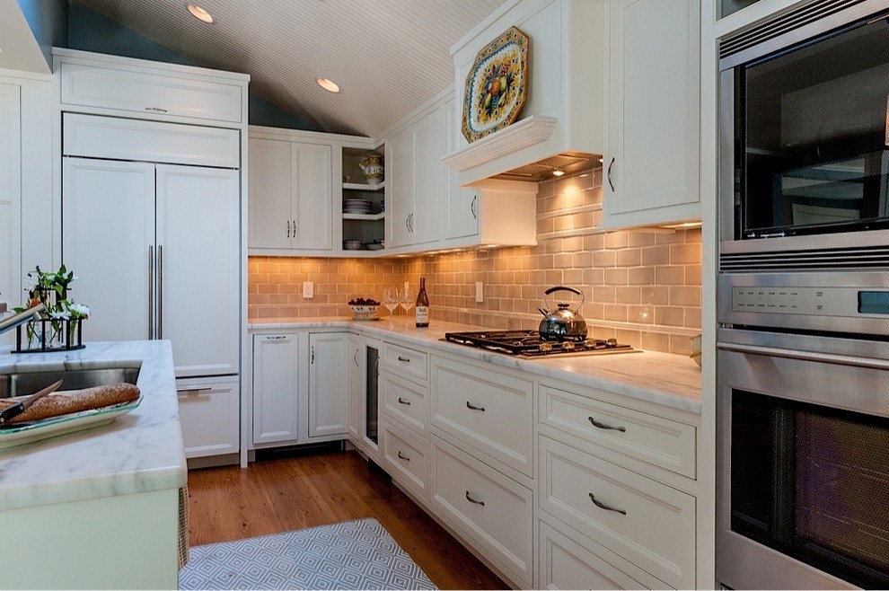 Inspiration for a mid-sized beach style galley separate kitchen in Tampa with an undermount sink, beaded inset cabinets, beige cabinets, marble benchtops, beige splashback, stone tile splashback, panelled appliances, medium hardwood floors and with island.