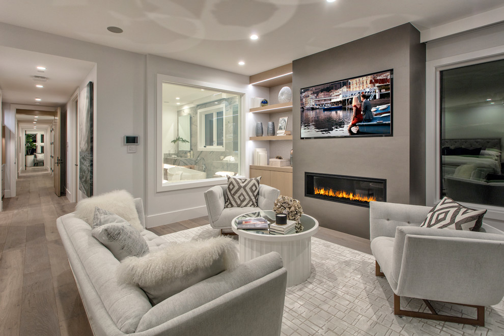 This is an example of an expansive traditional master bedroom in Orange County with grey walls, medium hardwood floors, a ribbon fireplace, a concrete fireplace surround and brown floor.