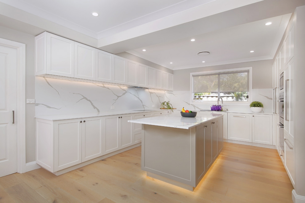 Inspiration for a large modern u-shaped eat-in kitchen in Sydney with an integrated sink, raised-panel cabinets, white cabinets, quartz benchtops, white splashback, stone slab splashback, panelled appliances, dark hardwood floors, with island, brown floor and white benchtop.