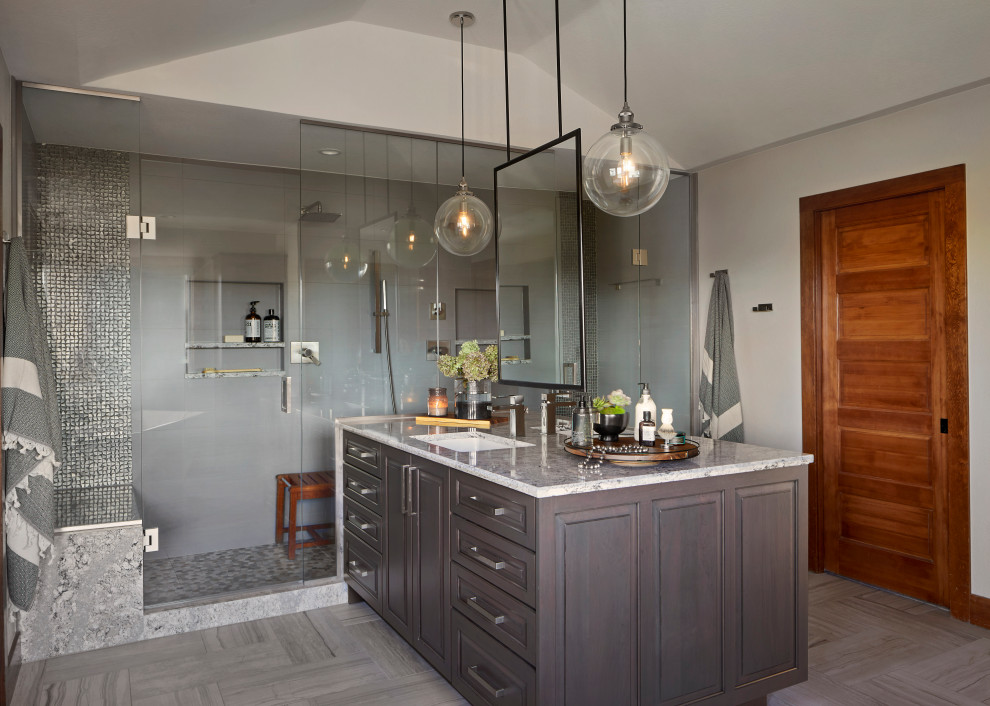 Inspiration for a large transitional master gray tile and porcelain tile porcelain tile and gray floor bathroom remodel in Denver with raised-panel cabinets, brown cabinets, gray walls, an undermount sink, a hinged shower door and gray countertops