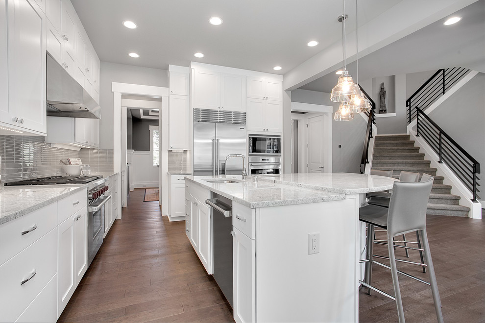 Inspiration for a large transitional galley eat-in kitchen in Seattle with an undermount sink, shaker cabinets, white cabinets, granite benchtops, grey splashback, glass tile splashback, stainless steel appliances, medium hardwood floors and with island.