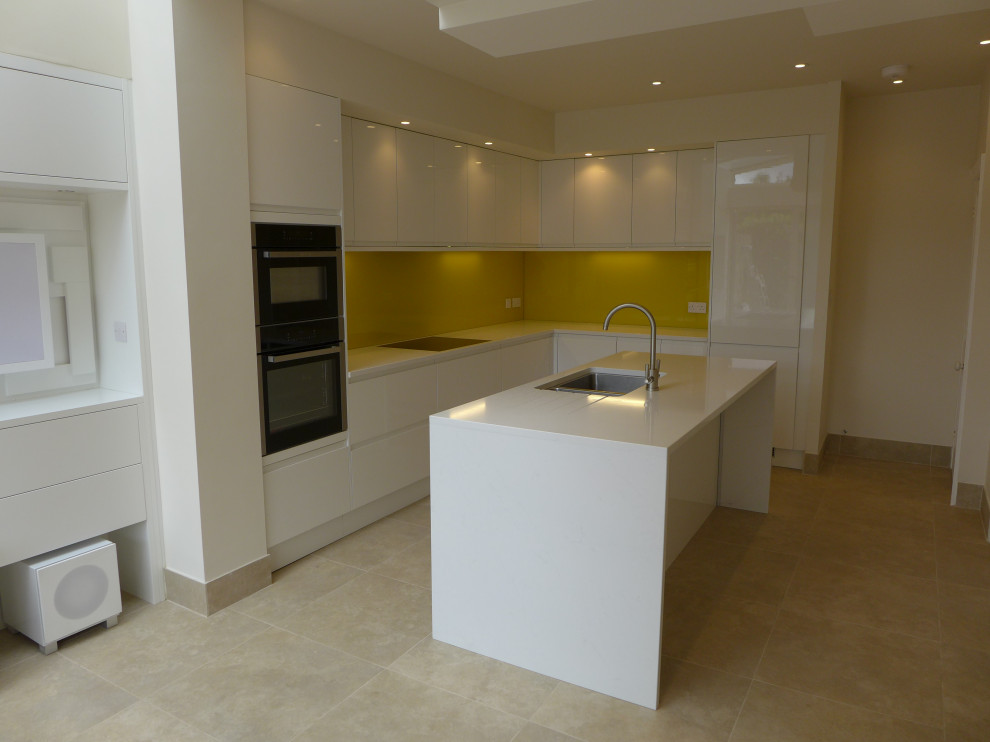 This is an example of a mid-sized contemporary l-shaped open plan kitchen in Other with an undermount sink, flat-panel cabinets, white cabinets, quartzite benchtops, yellow splashback, glass sheet splashback, stainless steel appliances, porcelain floors, with island, beige floor, white benchtop and vaulted.