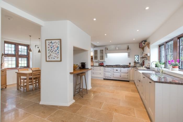 Photo of an expansive country l-shaped open plan kitchen in Edinburgh with a farmhouse sink, shaker cabinets, white cabinets, granite benchtops, panelled appliances, ceramic floors and no island.