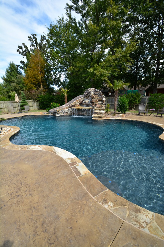 Mid-sized country backyard custom-shaped lap pool in Little Rock with a water slide and natural stone pavers.