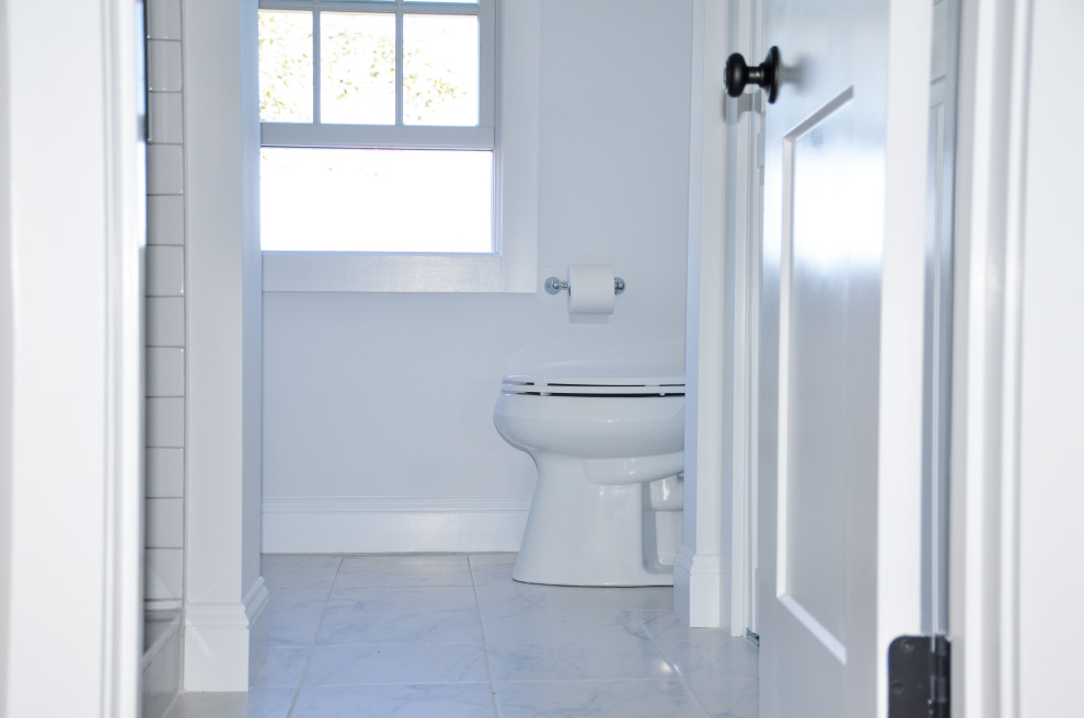 This is an example of a small traditional bathroom in Boston with white cabinets, an alcove shower, a two-piece toilet, white tile, subway tile, white walls, ceramic floors, a drop-in sink, granite benchtops, white floor, a sliding shower screen, white benchtops, a niche, a single vanity and a freestanding vanity.