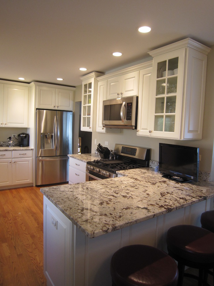 Inspiration for a mid-sized transitional medium tone wood floor eat-in kitchen remodel in Chicago with raised-panel cabinets, white cabinets, stainless steel appliances, a peninsula, a double-bowl sink and granite countertops