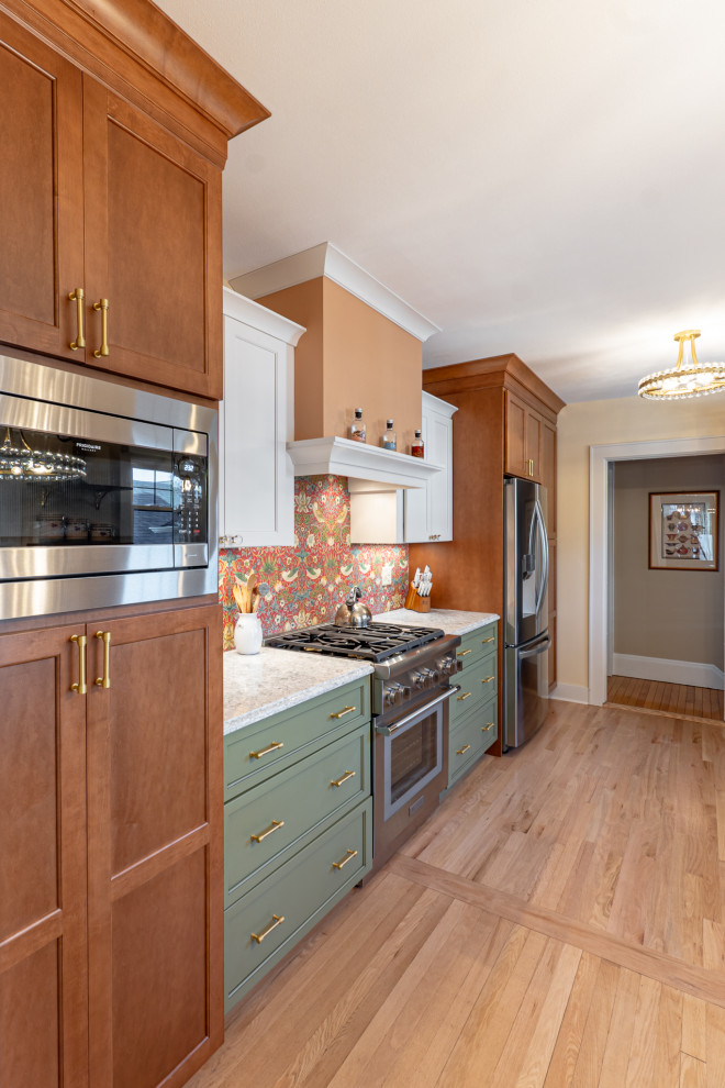 Photo of a mid-sized eclectic galley separate kitchen in Milwaukee with an undermount sink, shaker cabinets, green cabinets, quartz benchtops, multi-coloured splashback, stainless steel appliances, medium hardwood floors, no island, brown floor and multi-coloured benchtop.