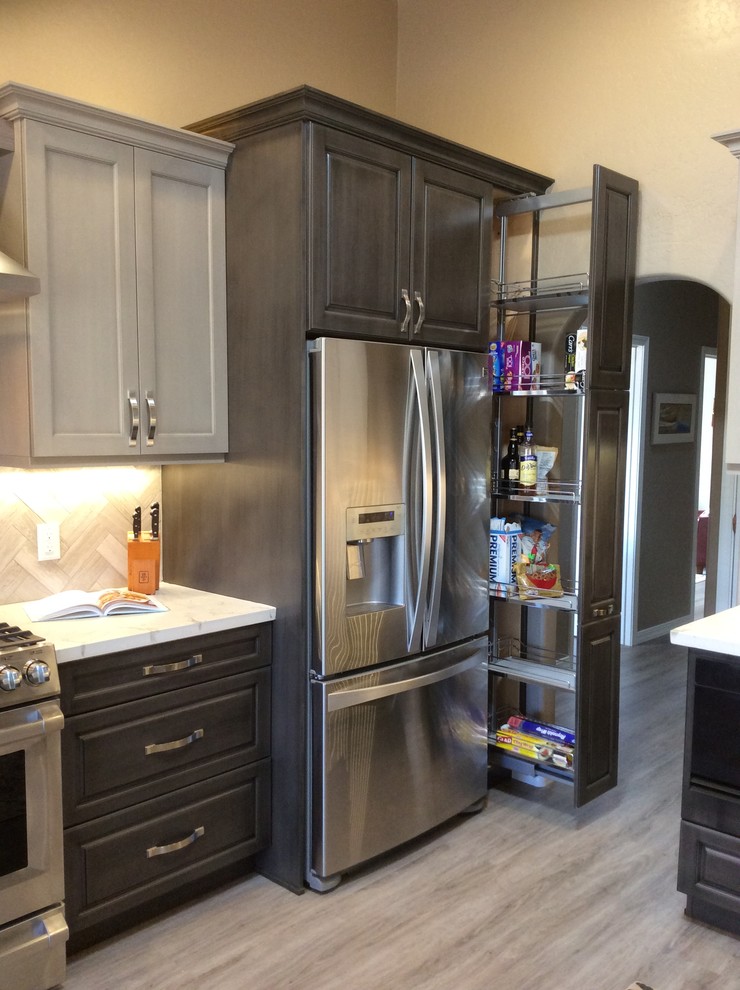 Mid-sized transitional dark wood floor and brown floor kitchen photo in Phoenix with raised-panel cabinets, dark wood cabinets, onyx countertops, brown backsplash, ceramic backsplash, stainless steel appliances and an island