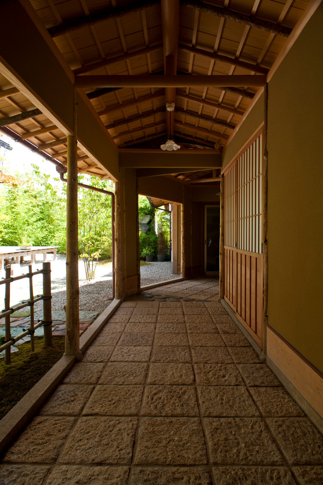 Exempel på en asiatisk veranda längs med huset, med naturstensplattor