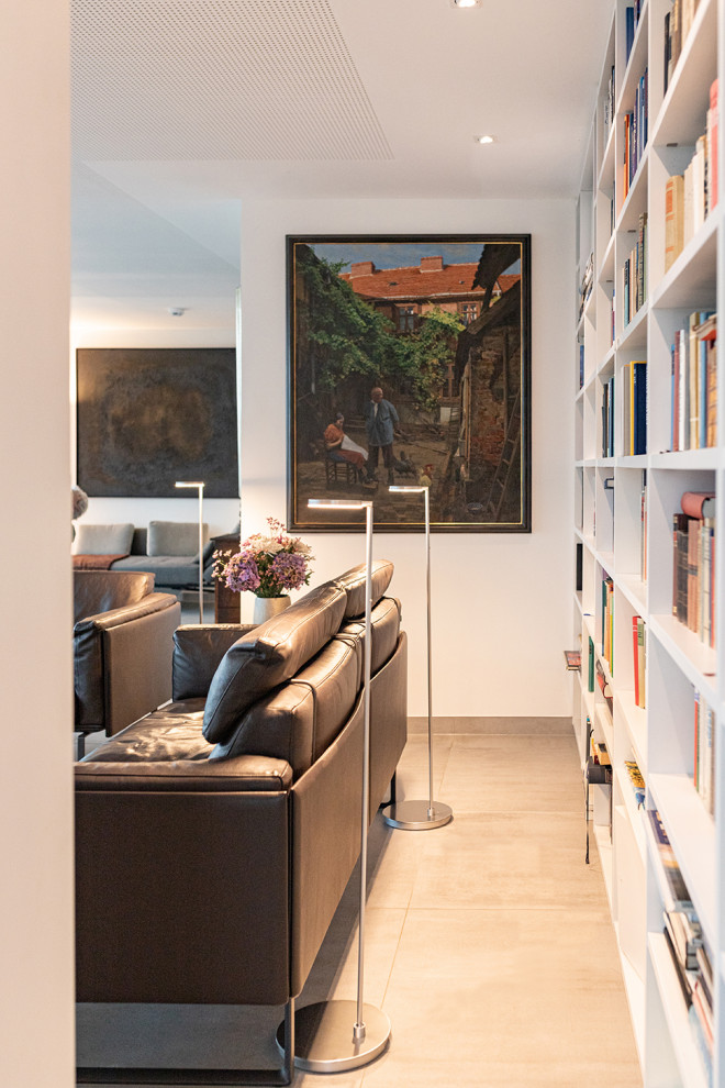 Imagen de sala de estar con biblioteca abierta moderna pequeña con paredes blancas, suelo de baldosas de cerámica, televisor retractable, suelo gris y papel pintado
