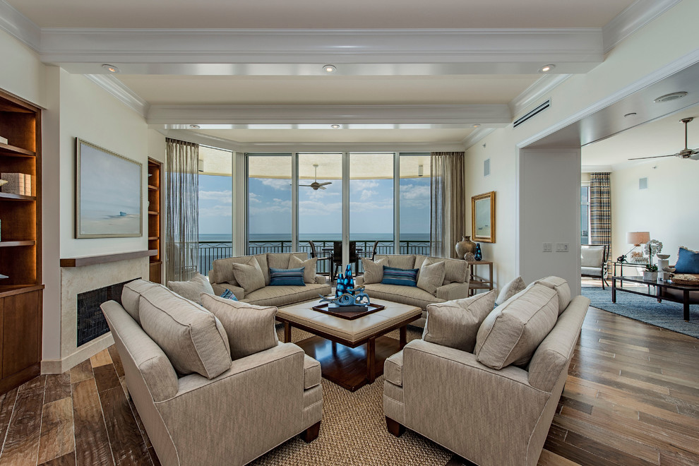 Photo of a large beach style formal open concept living room in Miami with beige walls, medium hardwood floors, a standard fireplace and no tv.
