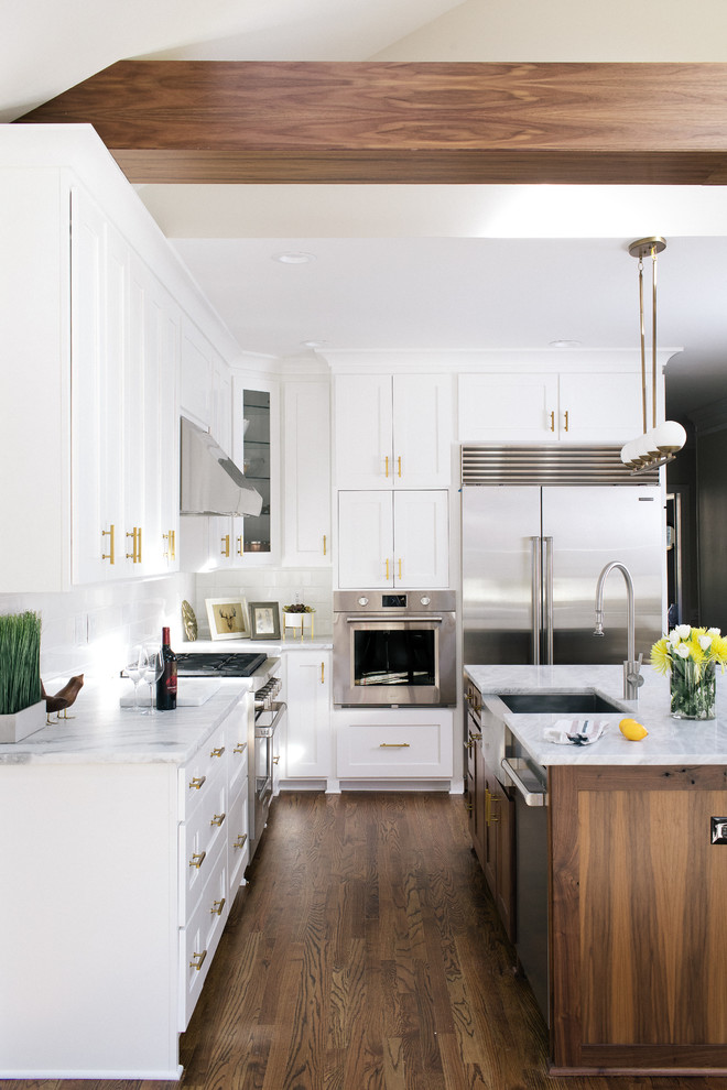 Photo of a large transitional l-shaped open plan kitchen in Atlanta with a farmhouse sink, shaker cabinets, white cabinets, marble benchtops, white splashback, ceramic splashback, stainless steel appliances, dark hardwood floors and with island.