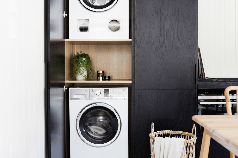 Small modern l-shaped laundry room in Sydney with black cabinets.
