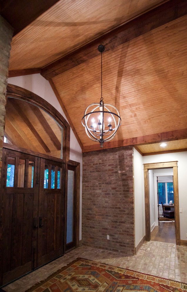Large mountain style brick floor foyer photo with a medium wood front door