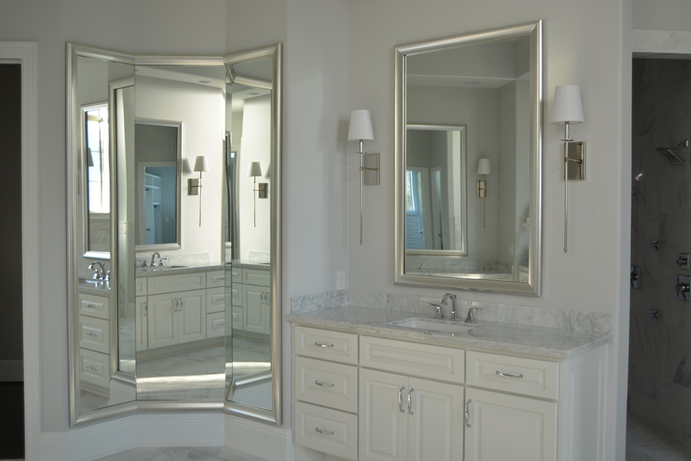 This is an example of a transitional master bathroom in Houston with raised-panel cabinets, white cabinets, a freestanding tub, an alcove shower, a two-piece toilet, white tile, marble, grey walls, marble floors, an undermount sink, marble benchtops, white floor and a hinged shower door.
