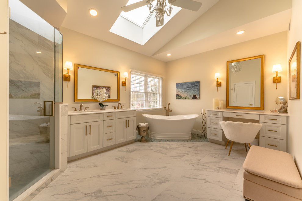 Large traditional master bathroom in Philadelphia with recessed-panel cabinets, white cabinets, a freestanding tub, a two-piece toilet, multi-coloured tile, porcelain tile, beige walls, porcelain floors, an integrated sink, engineered quartz benchtops, multi-coloured floor, a hinged shower door, white benchtops, a shower seat, a double vanity, a freestanding vanity and vaulted.