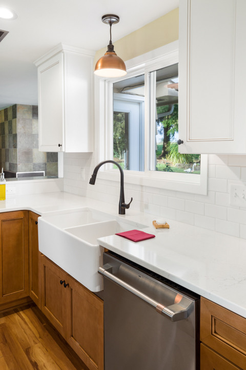 Eat-in kitchen - mid-sized transitional l-shaped medium tone wood floor and brown floor eat-in kitchen idea with a farmhouse sink, shaker cabinets, white cabinets, quartz countertops, white backsplash, subway tile backsplash, stainless steel appliances, an island and white countertops