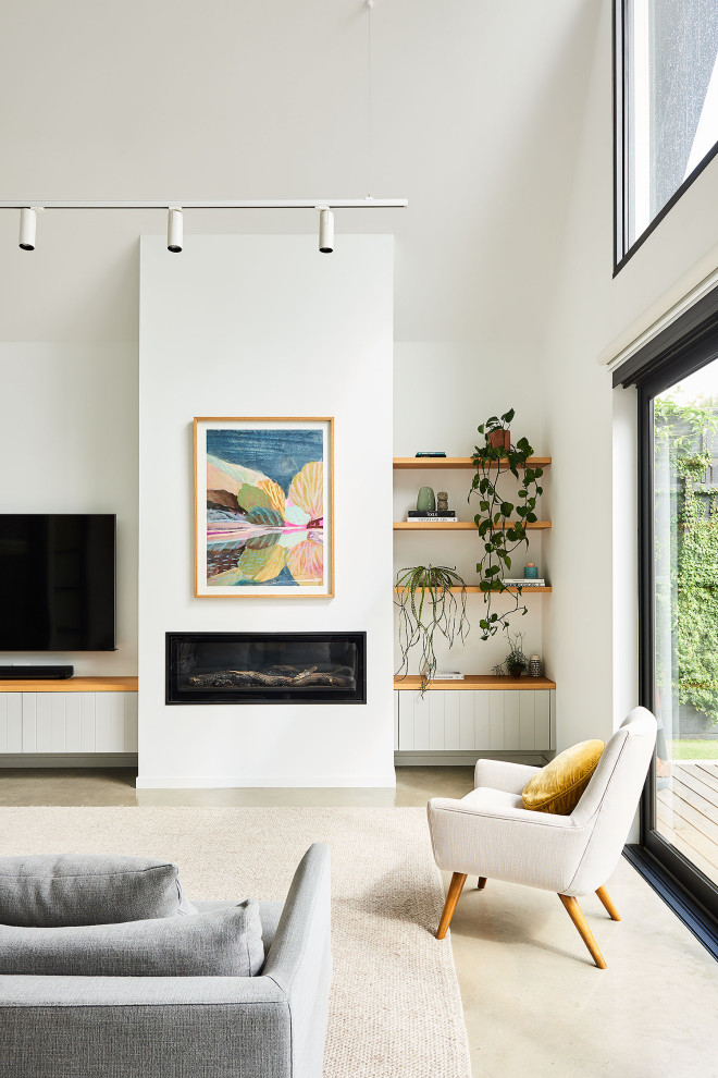 ジーロングにある中くらいなトロピカルスタイルのおしゃれなLDK (白い壁、コンクリートの床、標準型暖炉、漆喰の暖炉まわり、グレーの床、三角天井) の写真