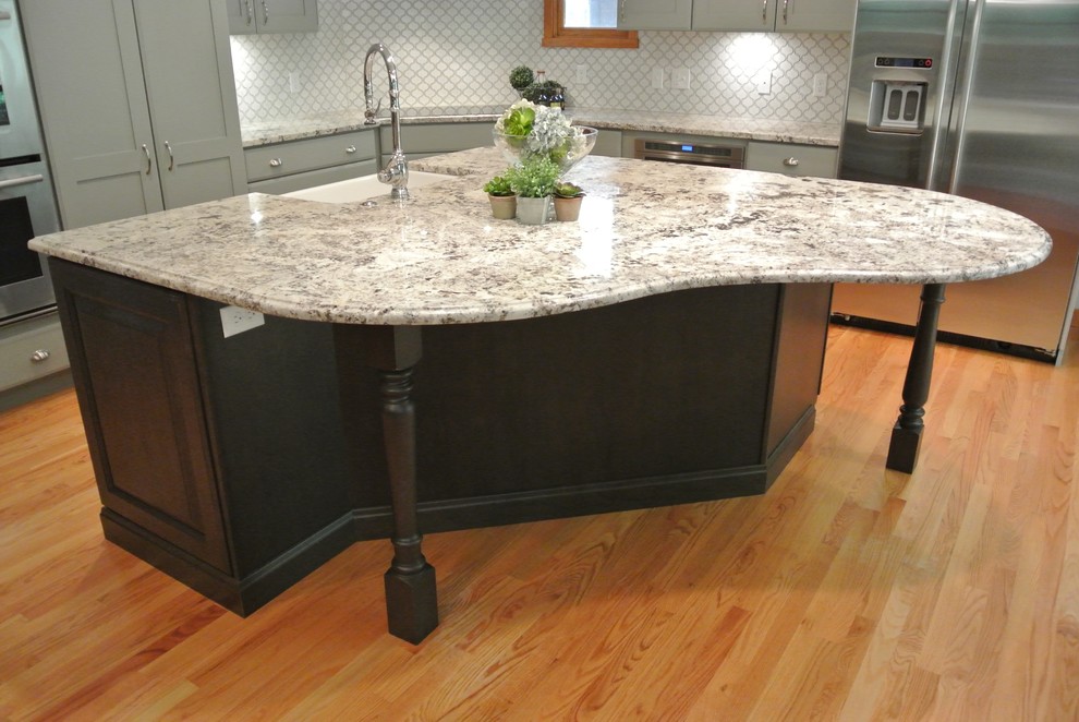 Large transitional l-shaped light wood floor eat-in kitchen photo in Boston with a farmhouse sink, shaker cabinets, gray cabinets, granite countertops, white backsplash, ceramic backsplash, stainless steel appliances, an island and gray countertops