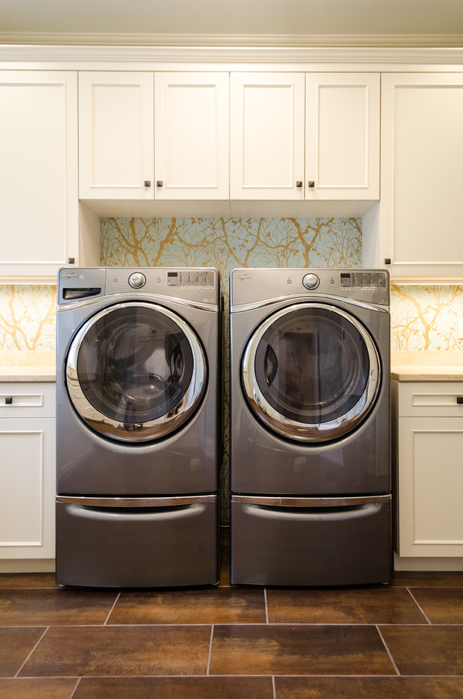 This is an example of a transitional laundry room in Cleveland with limestone benchtops, multi-coloured walls, porcelain floors and a side-by-side washer and dryer.