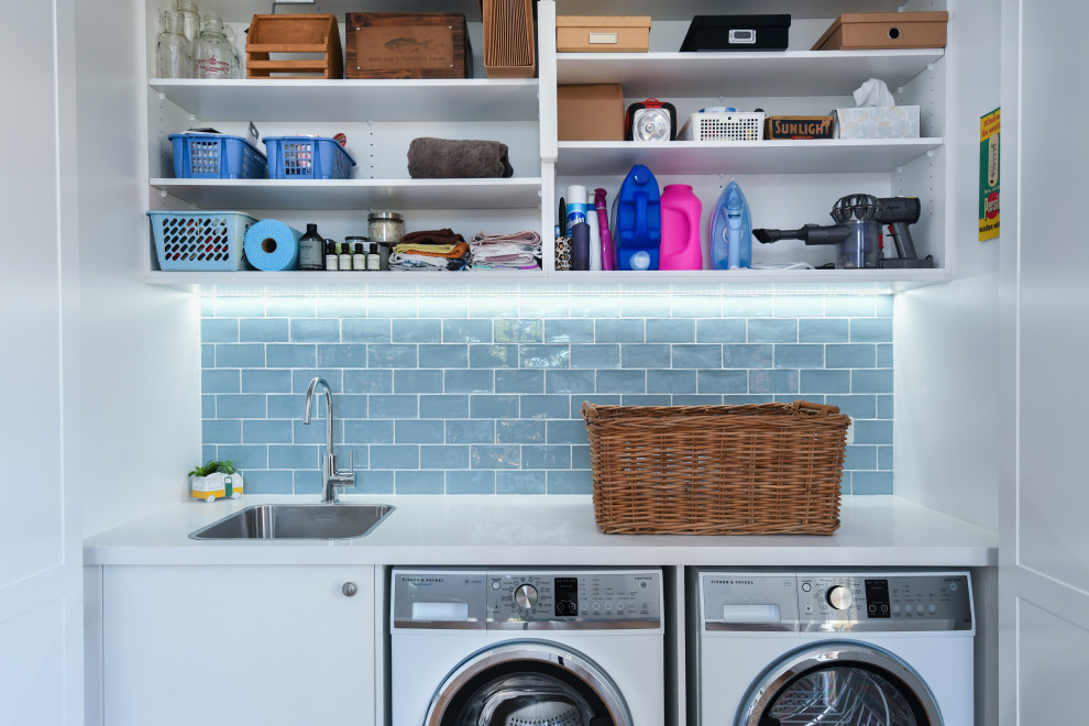 Design ideas for a small traditional single-wall dedicated laundry room in Sydney with a drop-in sink, shaker cabinets, white cabinets, quartz benchtops, blue splashback, subway tile splashback, white walls, ceramic floors, a side-by-side washer and dryer, blue floor and white benchtop.