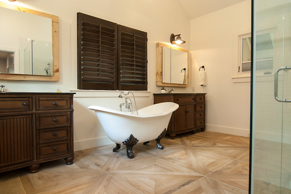Design ideas for a mid-sized master bathroom in Charlotte with beaded inset cabinets, dark wood cabinets, a claw-foot tub, white walls, light hardwood floors, a hinged shower door, an alcove shower, a two-piece toilet, terra-cotta tile, an undermount sink, granite benchtops and brown floor.
