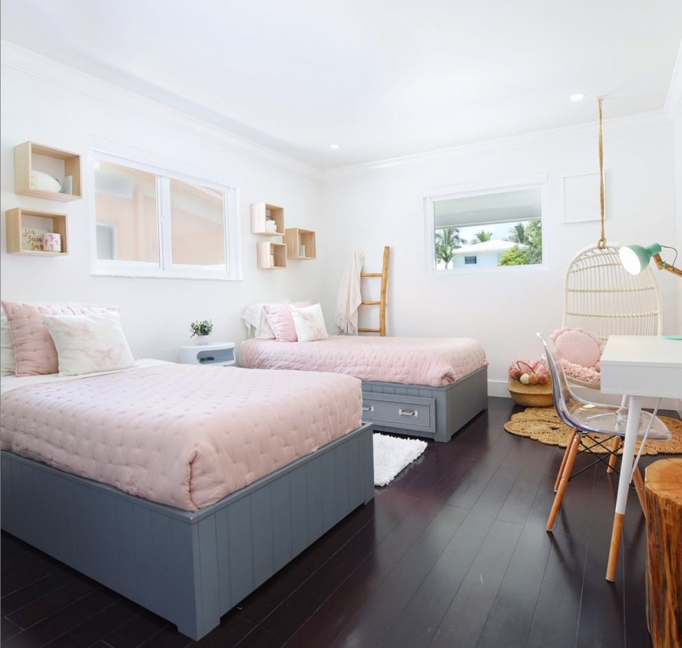 Photo of a large beach style kids' bedroom for kids 4-10 years old and girls in Miami with white walls, dark hardwood floors and brown floor.