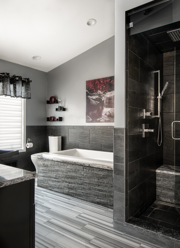 Photo of a large contemporary master bathroom in Detroit with recessed-panel cabinets, black cabinets, an alcove shower, gray tile, grey walls, marble floors, a drop-in tub, a two-piece toilet, ceramic tile, a vessel sink, engineered quartz benchtops, multi-coloured floor, a hinged shower door and multi-coloured benchtops.