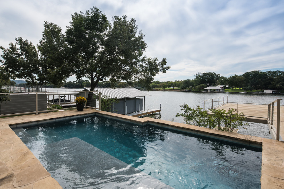 This is an example of a large transitional backyard pool in Austin with natural stone pavers.