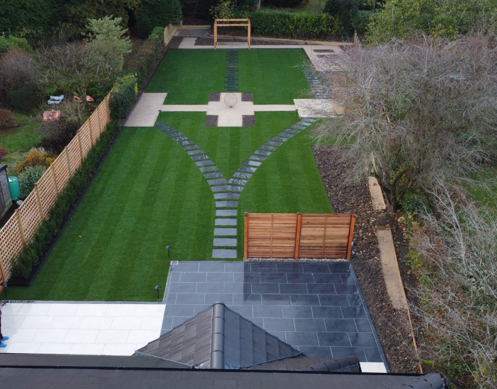 Design ideas for a large modern backyard full sun formal garden for summer in West Midlands with with lawn edging, natural stone pavers and a wood fence.