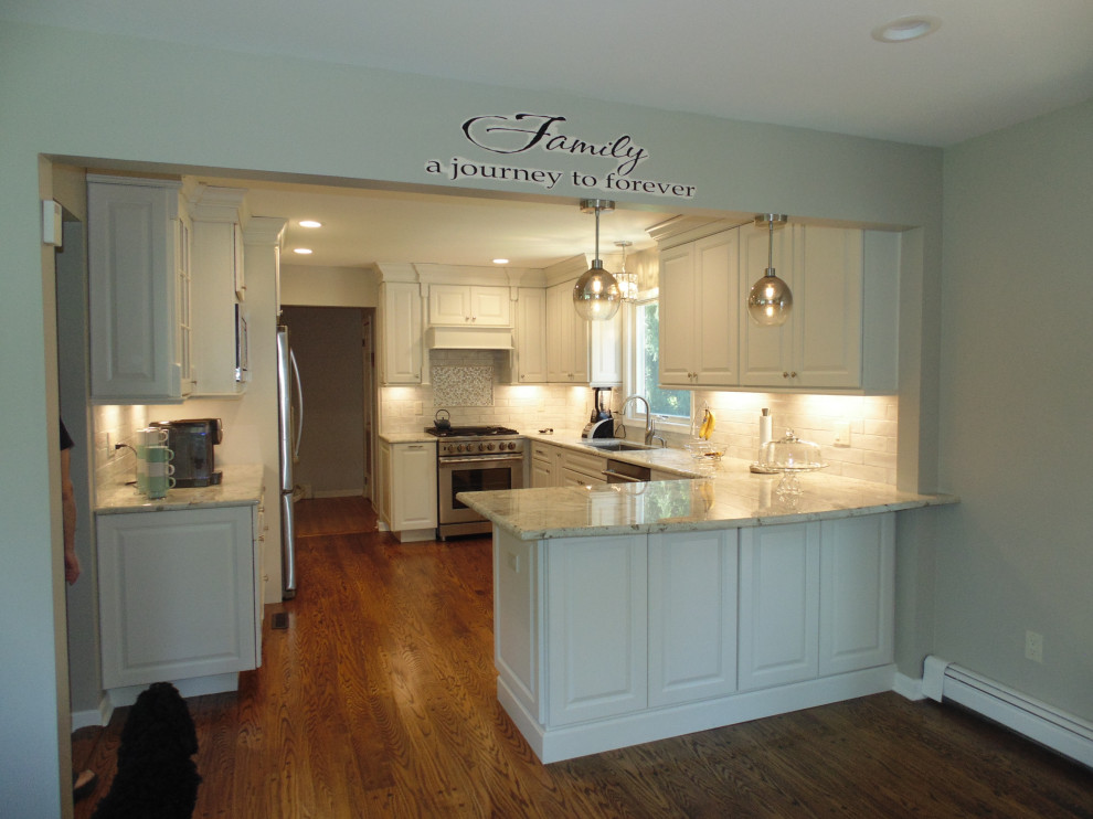 Example of a mid-sized transitional u-shaped medium tone wood floor and brown floor eat-in kitchen design with an undermount sink, raised-panel cabinets, white cabinets, granite countertops, white backsplash, subway tile backsplash, stainless steel appliances, no island and gray countertops