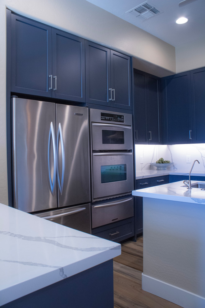Inspiration for a mid-sized transitional eat-in kitchen remodel in Phoenix with an undermount sink, shaker cabinets, blue cabinets, quartz countertops, white backsplash, quartz backsplash, stainless steel appliances, an island and white countertops