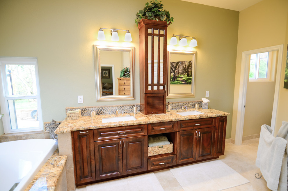 Inspiration for a large master bathroom in Tampa with an undermount sink, raised-panel cabinets, brown cabinets, granite benchtops, a drop-in tub, a corner shower, a one-piece toilet, brown tile, stone tile, green walls and travertine floors.