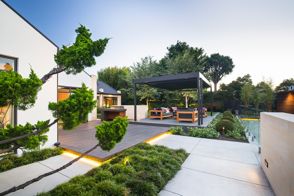 This is an example of a mid-sized contemporary backyard patio in Christchurch with an outdoor kitchen, concrete slab and a pergola.