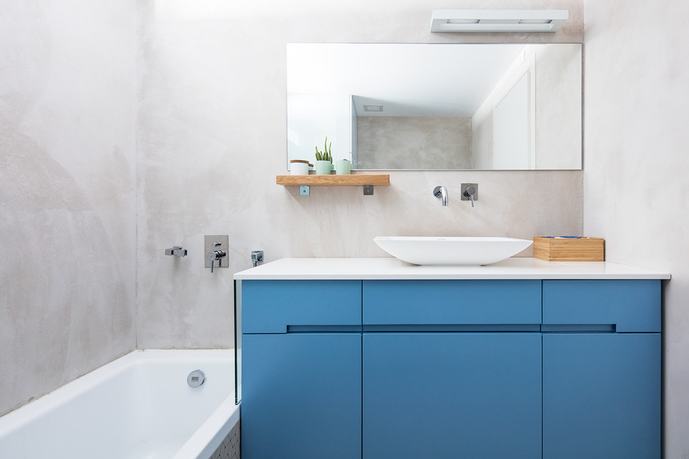 Design ideas for a contemporary bathroom in Calgary with flat-panel cabinets, blue cabinets, a drop-in tub, grey walls and a vessel sink.