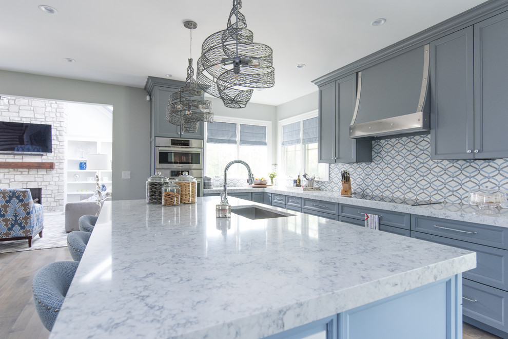 Large transitional medium tone wood floor eat-in kitchen photo with a single-bowl sink, shaker cabinets, gray cabinets, quartz countertops, multicolored backsplash, marble backsplash and paneled appliances