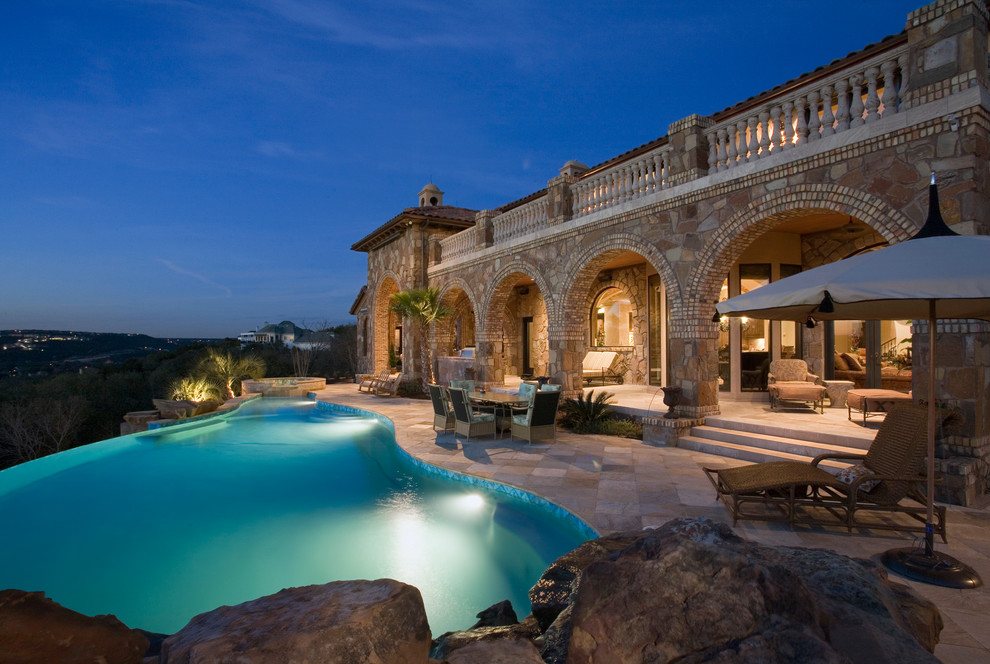 This is an example of a mediterranean custom-shaped infinity pool in Austin with a hot tub.