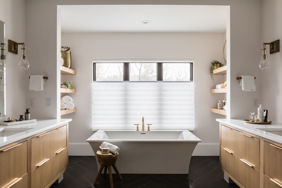 Transitional bathroom in Raleigh with flat-panel cabinets, light wood cabinets, a freestanding tub, white walls, an undermount sink, black floor, white benchtops, a double vanity and a floating vanity.