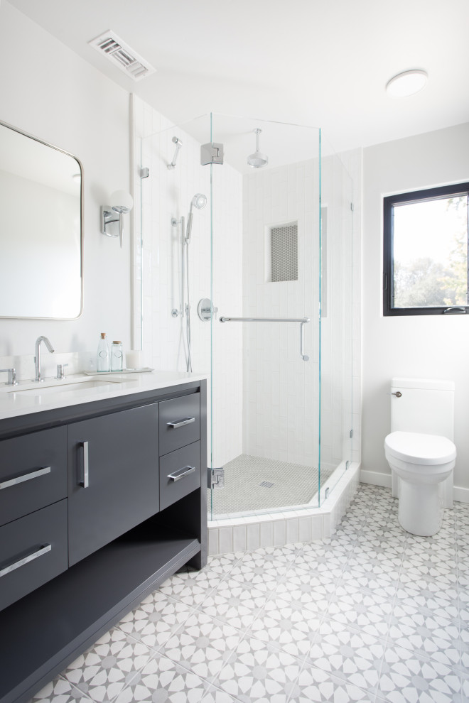 Mid-sized transitional 3/4 bathroom in Santa Barbara with flat-panel cabinets, grey cabinets, a corner shower, a one-piece toilet, white tile, subway tile, white walls, porcelain floors, an undermount sink, multi-coloured floor, a hinged shower door, white benchtops and marble benchtops.