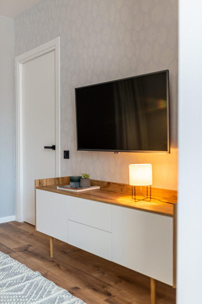 Идея дизайна: маленькая гостиная комната в современном стиле с серыми стенами, полом из ламината, телевизором на стене и обоями на стенах для на участке и в саду