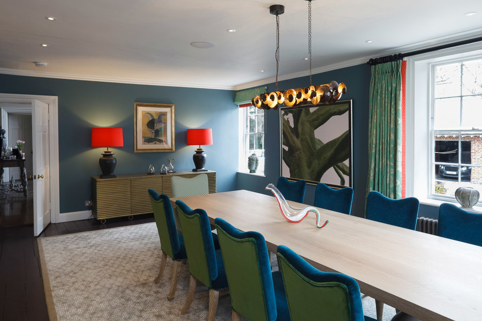 Large eclectic separate dining room in Cambridgeshire with green walls, painted wood floors and a metal fireplace surround.