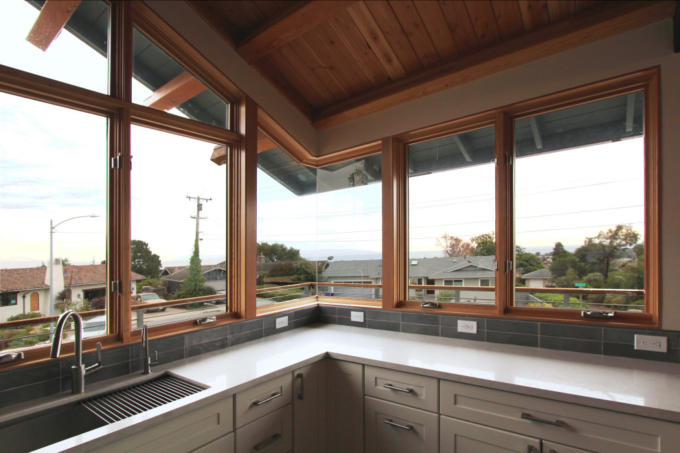 Open concept kitchen - mid-sized transitional l-shaped gray floor open concept kitchen idea with an undermount sink, shaker cabinets, white cabinets, quartz countertops, gray backsplash, ceramic backsplash, stainless steel appliances, an island and multicolored countertops