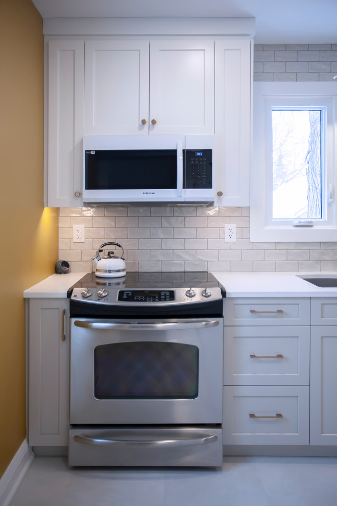 Mid-sized transitional single-wall eat-in kitchen photo with an undermount sink, shaker cabinets, white cabinets, quartz countertops, porcelain backsplash, stainless steel appliances, no island and white countertops