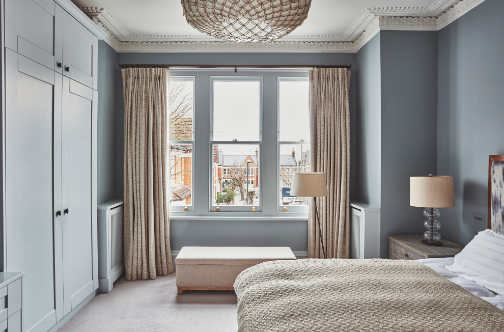 Mittelgroßes Modernes Hauptschlafzimmer mit blauer Wandfarbe, Teppichboden und beigem Boden in London