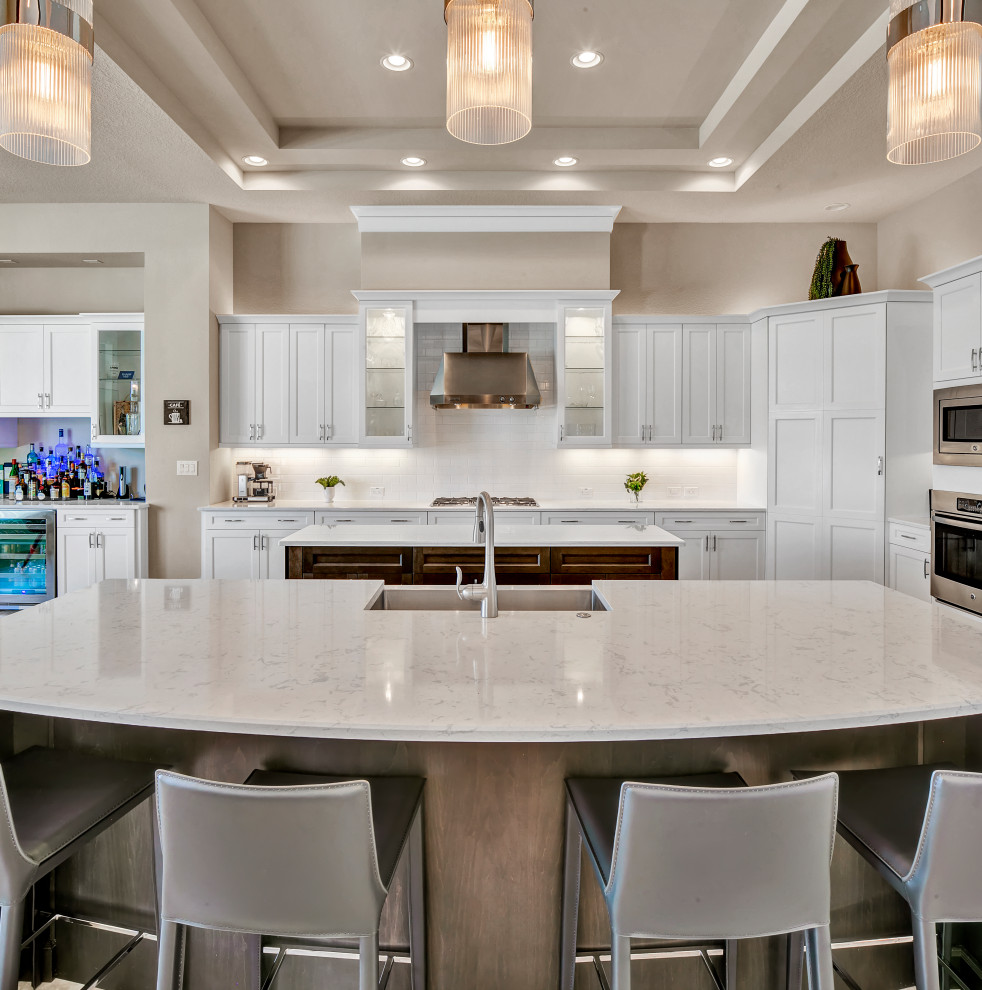 Large modern l-shaped kitchen/diner in Tampa with a submerged sink, shaker cabinets, white cabinets, engineered stone countertops, white splashback, stainless steel appliances, travertine flooring, multiple islands, multi-coloured floors, white worktops and a drop ceiling.