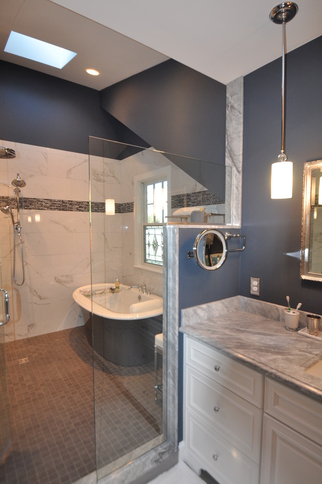 Photo of a large traditional master wet room bathroom in Boston with raised-panel cabinets, white cabinets, a freestanding tub, a two-piece toilet, white tile, porcelain tile, grey walls, porcelain floors, an undermount sink, marble benchtops and grey floor.