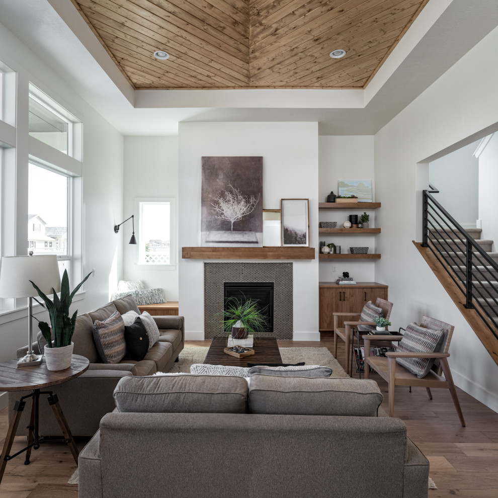 Foto di un soggiorno tradizionale con pareti bianche, pavimento in legno massello medio, camino classico, cornice del camino piastrellata, pavimento marrone e soffitto ribassato